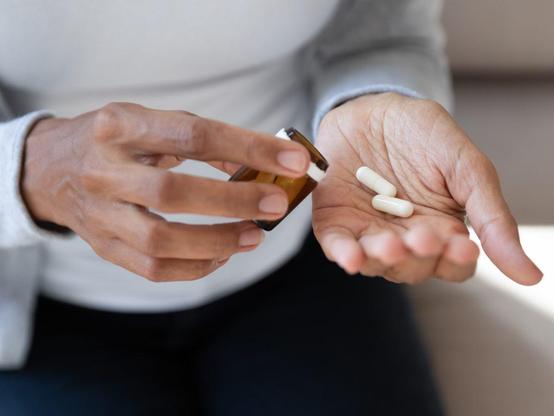 Photograph of a person measuring out pills from a bottle into their hand