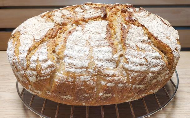rustikales Brot mit aufgebrochener Kruste auf dem Auskühlrost.