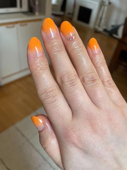 Kynnet joissa kärjet ovat oranssit ja nimettömän sormen kynnessä kolme timanttia