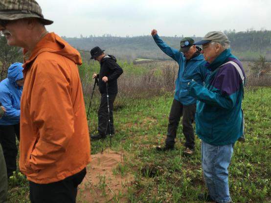 A half-dozen field trip goers poke around the south unit of the Namekagon Barrens state wildlife refuge, which has recently undergone a prescribed burn. One of the participants raises his arm as the group sings "On Wisconsin."