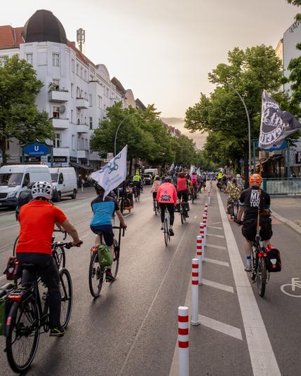 Fahrradfahrende auf der Hermannstraße nutzen den neuen Radweg, getrennt durch Poller vom Autoverkehr, bei Dämmerung in der Stadt