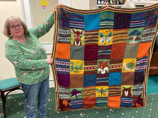 Woman holding up a woodland themed blanket
