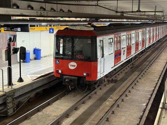 Metro de la serie 2100, frontal rojo y lateral blanco con las puertas en rojo, detenido en El Maresme | Fòrum, se ve en el testero el número de turno: el 406