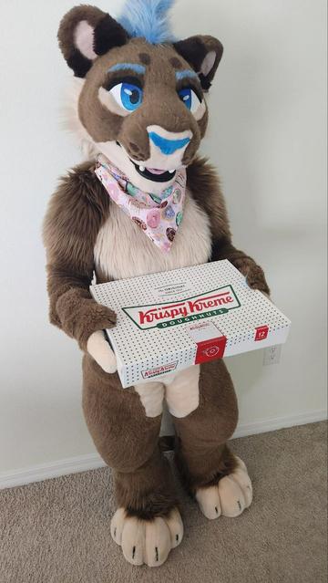Lioness fursuiter holding box of Krispy Kreme donuts