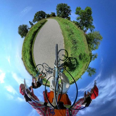 One of a series of photographs in which two people are pictured hiking, biking, and kayaking throughout a beautiful and verdant state park in central Minnesota under cloudy blue late-summer skies.
