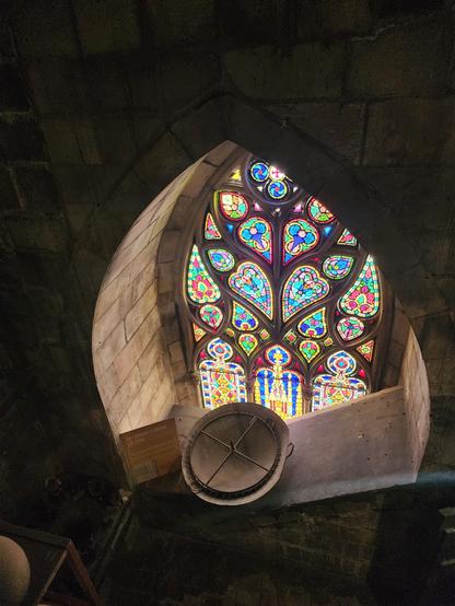 top section of an outward-facing pointed-arch stained glass window with very colorful floral and abstract designs. This was taken while descending the stairs from the top of the cathedral.