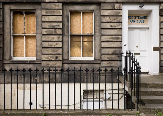 An Edinburgh new town flat, formal of design but worse for wear after what look like perhaps a few unhappy years. The windows are broken and boarded up on the inside. Above the door is a sign:

Rod Stewart Fan Club