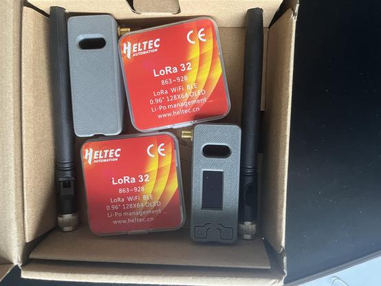 Ein geöffnetes Packchen mit 2 verpackten LoRa32-Heltec-Devices und 2 schon in 3-D-gedruckte Gehäuse eingebaute Einheiten einschließlich Antennen!