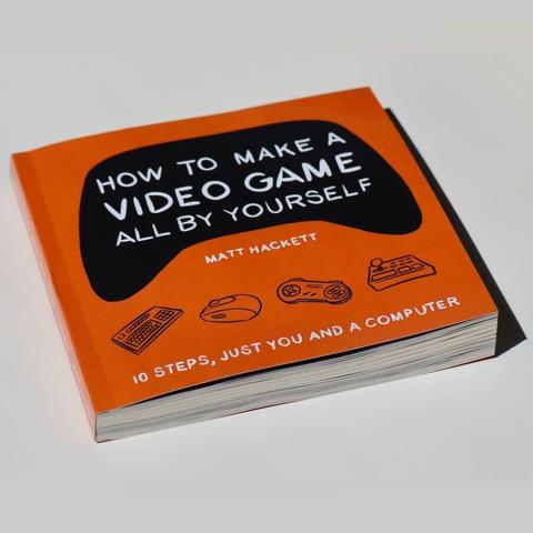 A paperback copy of How to Make a Video Game All By Yourself slightly tiled photographed in a white void.