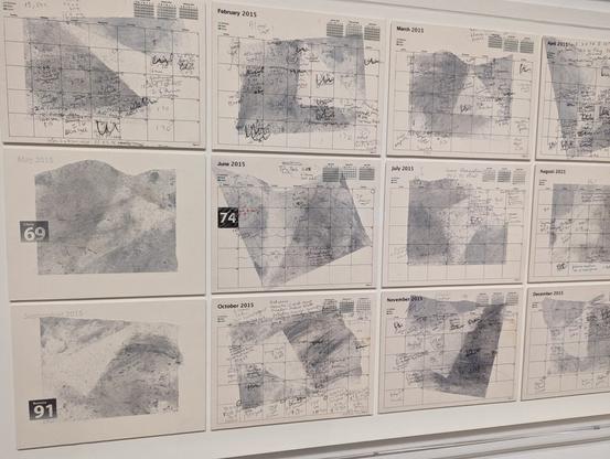 A grayscale series of calendars on a wall with gradients behind them in different shapes. Cursive writing shows up sporadically on different calendar dates. Deaths are marked with black days and large white numbers.
