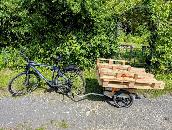 Fahrrad mit Anhänger auf dem Paletten geladen sind.