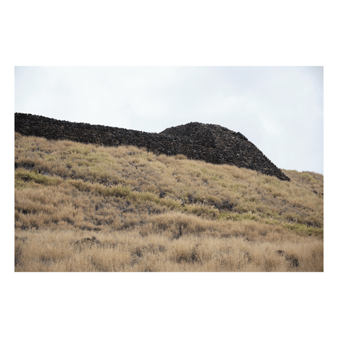 stacked stone sacred structure on top of grassy hill in hawaii