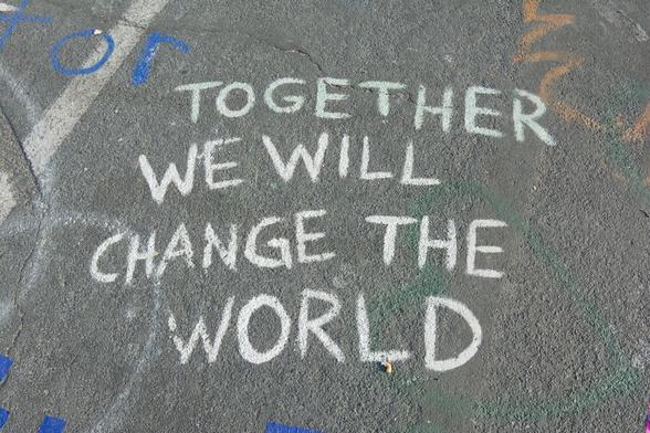 Chalk writing on pavement that says, "Together we wil change the world." By Priscilla Gyamfi via https://unsplash.com/photos/text-xVRIFWOBK3U.