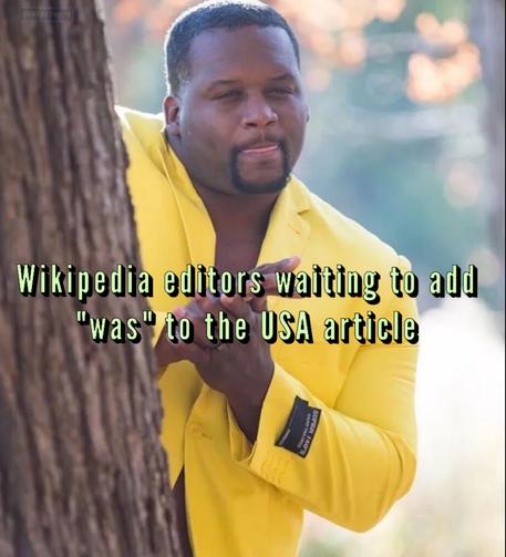 Anthony Adams wearing a yellow suit and hiding behind a tree while rubbing his hands. Text reads "Wikipedia editors waiting to add "was" to the USA article"