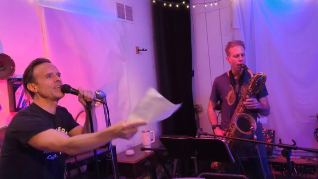 Two people one talking into mix one playing sax