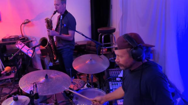 Person playing drums and person playing sax