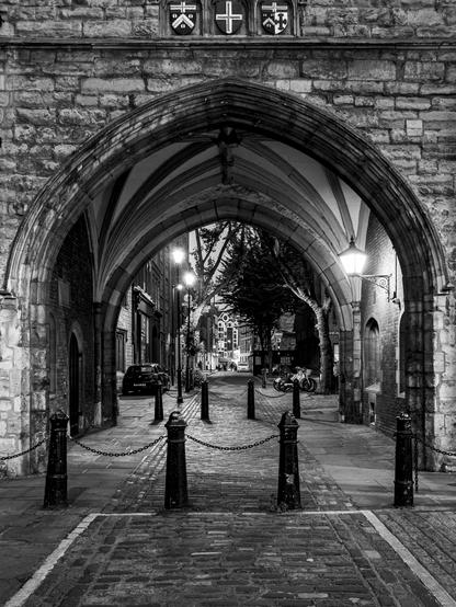 Street lanterns in an old stone passage in black and white at night.