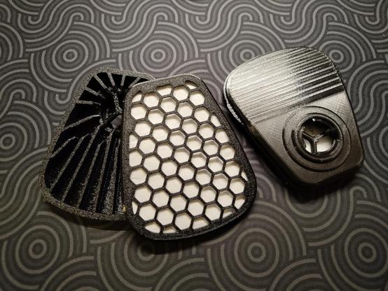 Dust filter capsules for a 3M mask lying on my desk, one is partially disassembled.