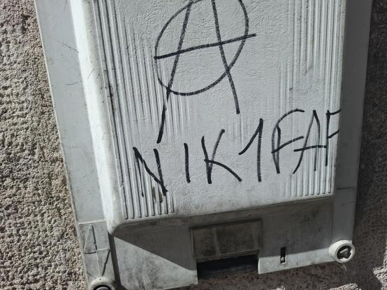 Photo d'un tag signé anarchiste avec écrit en majuscules nik1faf (nique un faf)