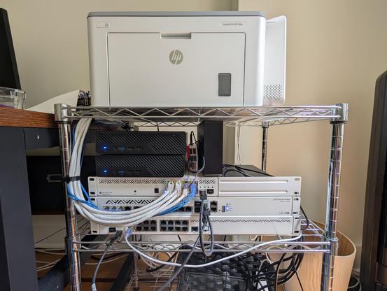 My homelab, with:

 * two Minisforum MS-01 Mini PCs (i9-13900H, 96GB RAM, bottom 2x4TB top 2x2TB NVMe)
 * a Raspberry Pi 4 (4GB) and a Seagate 24TB hard drive
 * MikroTik CCR2004-16G-2S+ (bottom router), CRS312-4C+8XG-RM (middle, core switch), CSS610-8P-2S+IN (top, PoE AP switch)
 * HP LaserJet Pro M118dw
 * T-Mobile G4SE router

Not pictured: five MikroTik WAP ax, L2TP VPN for my static IPv4/IPv6.