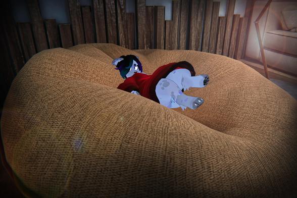 The photo shows an anthropomorphic furry character, wearing a red dress, lying on a large, beanbag-like chair or cushion. The character appears relaxed or possibly sleeping. The setting appears to be indoors, in a room with wooden walls and a partially visible sofa in the background.