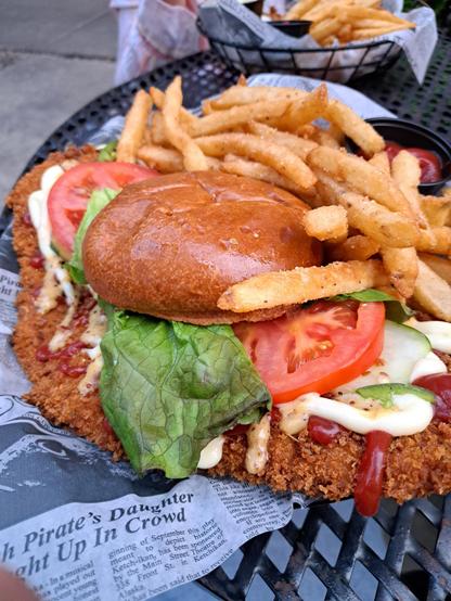 A sandwich with a crunchy tenderloin patty beneath it, about 5 times the size of the bun. Truly massive!