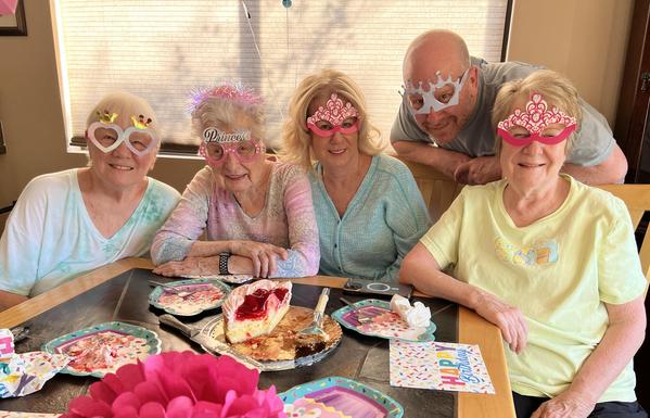 Four women and one man are wearing festive birthday glasses at a birthday celebration.