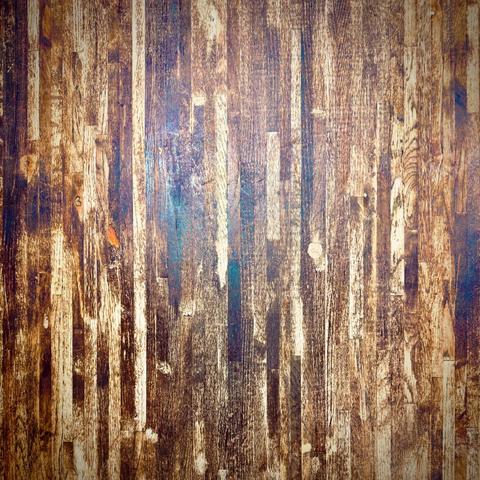 Vertical, pressed slats of wood fill the frame in many different shades, as a single bright light reflects off their overall smoothed surface.