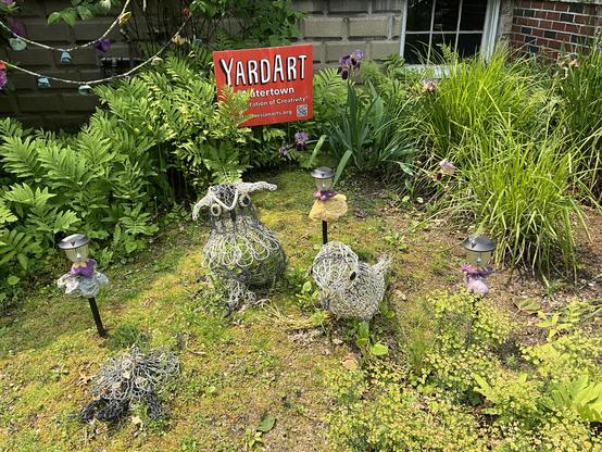 orange yardart sign garden scene with purple and yellow irises three knitted wire wire sculptures needlefelted flowers in different colors mounted on solar patio lights