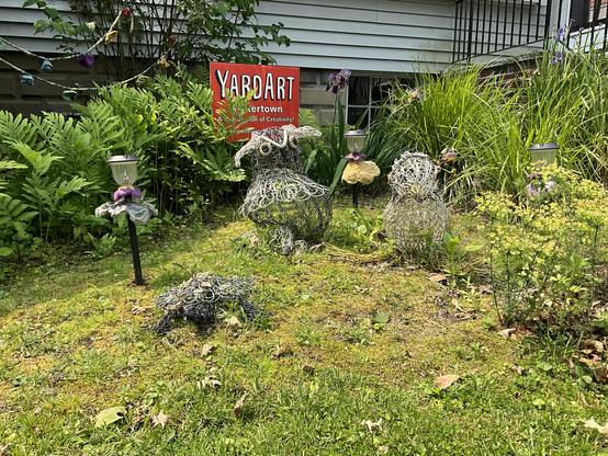 orange yardart sign garden scene with purple and yellow irises three knitted wire wire sculptures needlefelted flowers in different colors mounted on solar patio lights