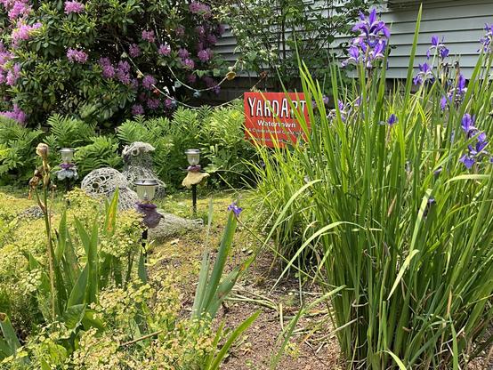 side view orange yardart sign garden scene with purple and yellow irises three knitted wire wire sculptures needlefelted flowers in different colors mounted on solar patio lights