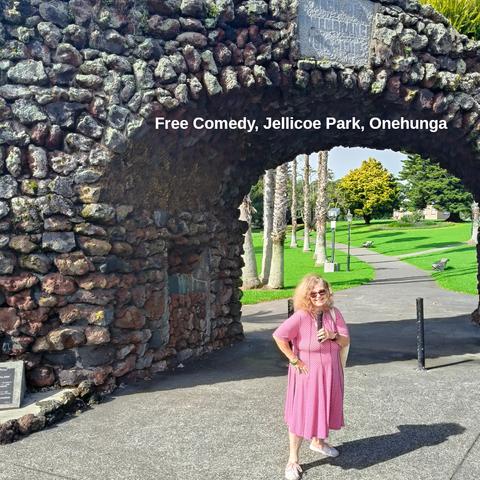 Tessa Clement stands in front of the memorial arch at Jellicoe Park, Onehunga. She is holding a microphone.