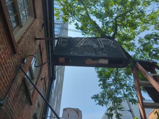 The EAR Inn with the funky "R "on the right. Black chipped paint metal box sign, ladder nearby, sign bottom pulled off so that the wood blocks holding transformers are exposed.