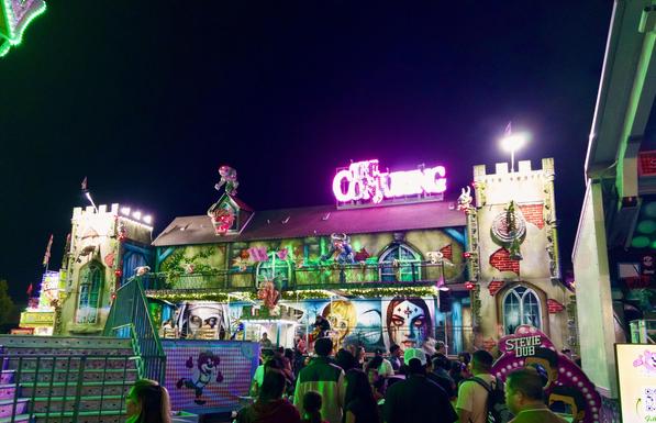 Closeup of the dark ride called “The Conjuring”, all lit up at night.
