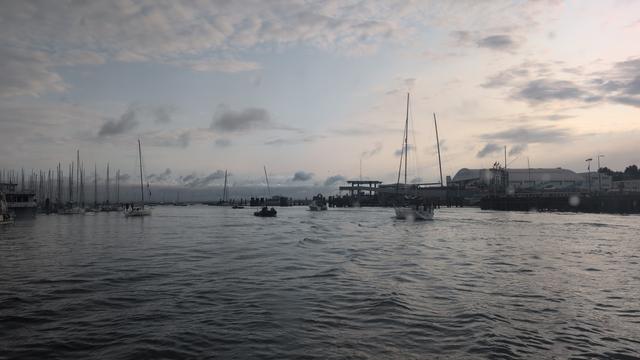 A picture from the Cowes Floating Bridge showing boats heading down the River Medina into the Solent. The sky is light but with ominous clouds on the horizon