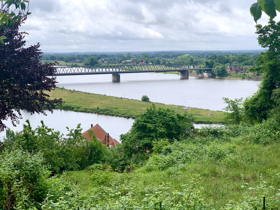 Im Vordergrund die Mündung des Elbe-Lübeck-Kanal in die Elbe, hinter Grün und einem Haus. Dahinter die Elbe mit der Brücke in Lauenburg. Von erhöhter Perspektive aus am 28.05.25..