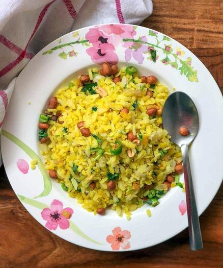 Une assiette de poha, plat traditionnel indien de riz aux oignons, épices, aromates et cacahuètes