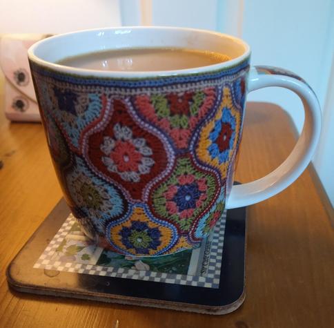 Mug of tea on a bedside cabinet with a crochet pattern design