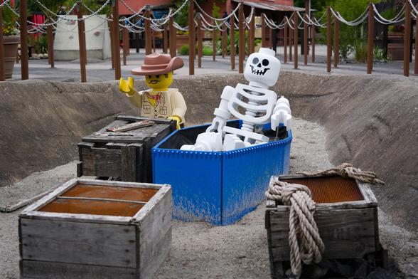 Photo of large lego figurines of an explorer/Johnny Thunder and a skeleton near boxes