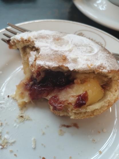 A close up of the cut open pasticciotto pastry reveals the creme and cherry filling within