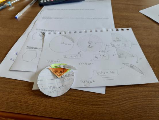 A imagem mostra uma mesa de estudo com vários papéis e materiais escolares. O tema principal dos exercícios é geometria, mais especificamente setores e segmentos circulares.

Há folhas com desenhos e cálculos geométricos. Estão desenhados círculos com triângulos inscritos e setores circulares. As fórmulas que aparecem nas folhas são: área do círculo igual a pi vezes o raio ao quadrado, área do setor igual à área do círculo multiplicada pelo ângulo e dividida por 360, área do triângulo igual a raio vezes raio dividido por 2, e a área do segmento circular é a diferença entre a área do setor e a área do triângulo.

Os valores usados como exemplo são: raio igual a 5 centímetros, área do círculo igual a 78,50 centímetros quadrados, área de um setor de 90 graus igual a 19,63 centímetros quadrados, área do triângulo igual a 12,50 centímetros quadrados, e área do segmento circular igual a 7,13 centímetros quadrados.

Há também um círculo de papel recortado, com um setor pintado de laranja, representando um ângulo de 90 graus. Nesse recorte estão escritas as mesmas fórmulas e valores que aparecem nas folhas.

Além disso, vê-se parte de uma calculadora no topo da imagem, algumas canetas e outros materiais escolares sobre a mesa. Também é visível parte de um exercício com um polígono regular, que parece ser um heptágono.