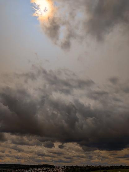 De gros nuages noirs arrivent.
Le soleil est tout juste caché par un bout de nuage.
Du ciel bleu entre le soleil et les méchants nuages.