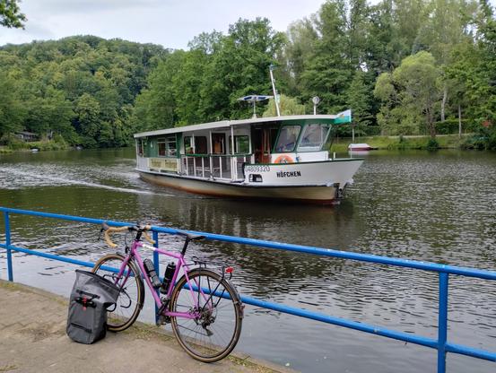 Ein Fährschiff kommt am Anleger an, das Fahrrad lehnt daneben am Geländer