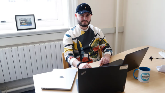 Photo: Nathaniel Fried, apparently a successful tech entrepreneur (obvious good at hiding himself as most people have never heard of him) sits at a desk with two open laptops and one close one in front of of him