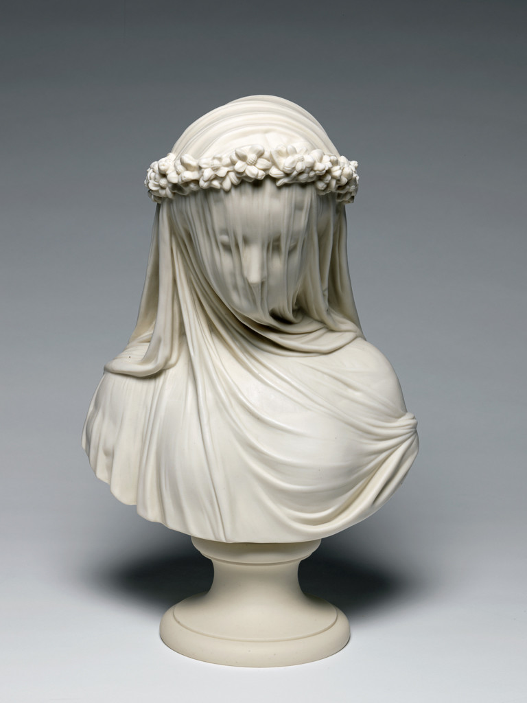 From the museum website: “Parian porcelain, slip cast bust of 'The Bride'. The circular socle is made separately and is held to the bust by a brass screw, nut, and washer. The bride faces front and looks downwards. She has a veil over her head which falls down over her face and breast at the front, and over her shoulders at the back. It is held in place by a wreath of orange-blossom flowers tied at centre back with a bow.” (Socle: a base for a small sculptures.)