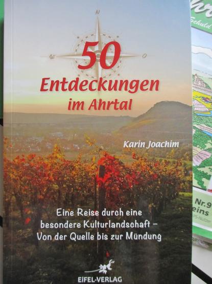 Buchcover. Foto: Blick über Weinberge im Herbstkleid Richtung Landskrone im Ahrtal zwischen Ehlingen und Heimersheim. Titel: Karin Joachim, 50 Entdeckungen im Ahrtal, Eine Reise durch eine besondere Kulturlandschaft - Von der Quelle bis zur Mündung.