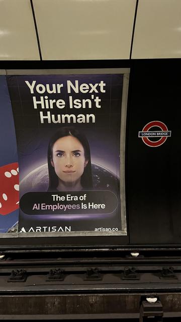 A poster displayed in a subway station features a woman with a serious expression, accompanied by the text "Your Next Hire Isn't Human" and "The Era of AI Employees Is Here," promoting AI solutions by a company named Artisan.