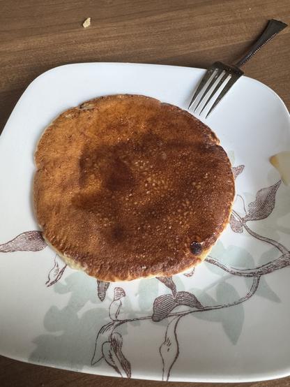 A perfectly round pancake on a plate, with syrup.
