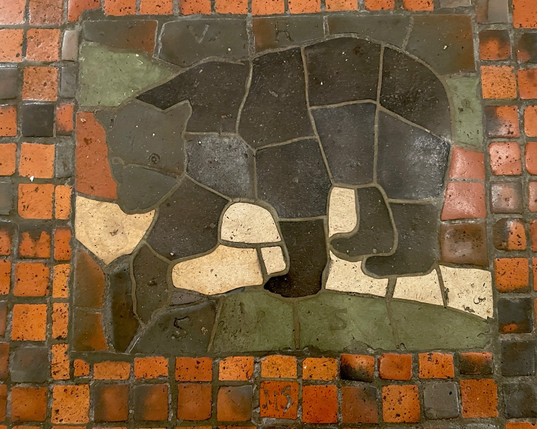 multicolor floor tile mosaic, side profile of a black bear, labeled “URSUS” and numbered “115”