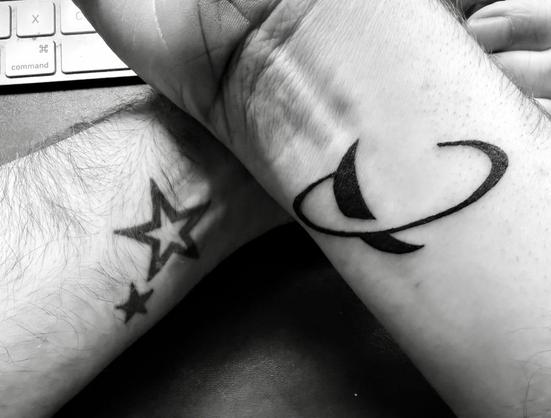 Left wrist: two stars; right wrist: Saturn